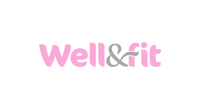 Sporty smiling woman doing planks on pilates ball while her personal trainer crouching next to her and cheering for her.